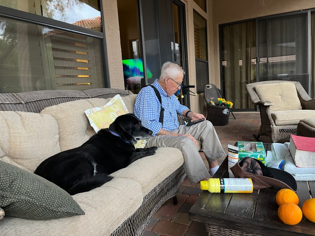 Dog and man sitting on patio furniture