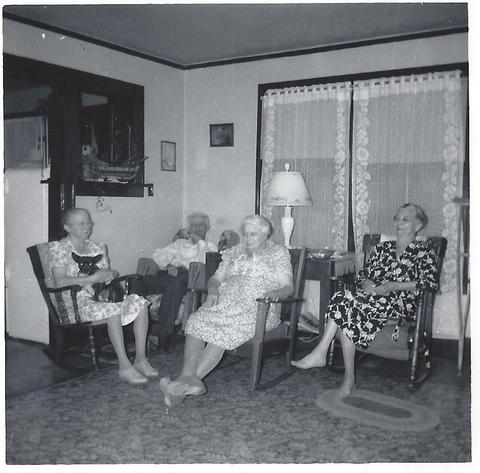 Three adults sitting inside on chairs with dog